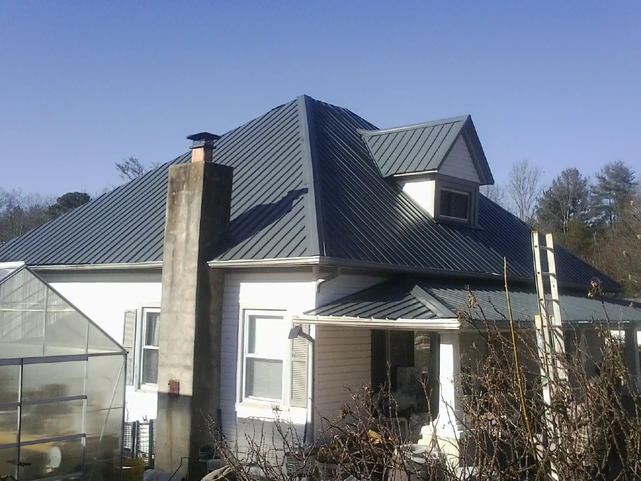 Dark blue standing seam metal roof on a white farmhouse with dormer — Slate & Tile Roof Repair by Roofing Brothers in Ho Ho Kus