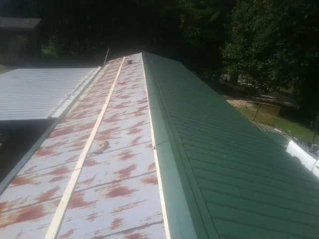Old rusted panels beside newly installed green metal roofing — Wind Damage Roof Repair by Roofing Brothers in Ho Ho Kus