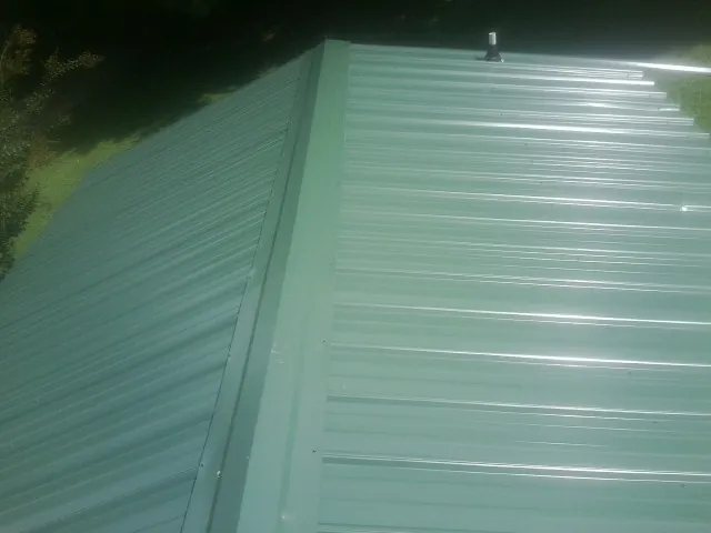 New green metal panels meeting at the ridge of a roof — Flat Roof Repair work by our crew in Ho Ho Kus