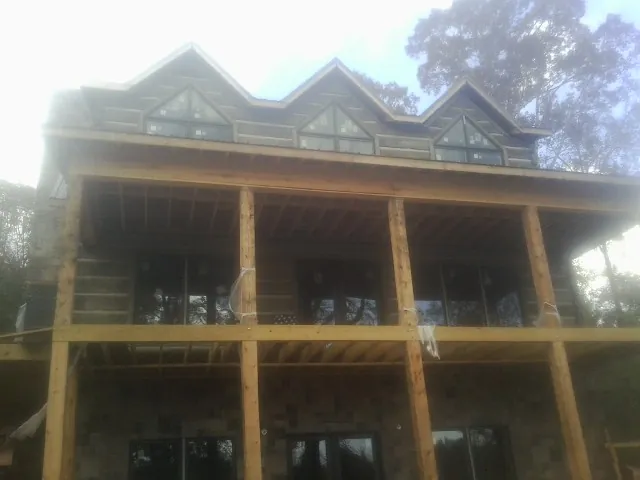 Dormers and porch framing on a large log home under construction — Roof Coating work by our crew in Ho Ho Kus