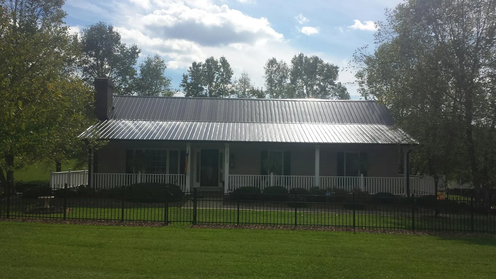 Gray metal roof on a brick ranch with a full width front porch — Gutter Guard Installation work by our crew in Ho Ho Kus