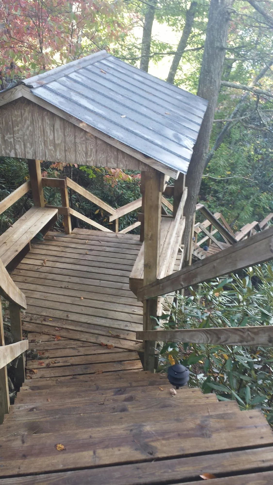 Metal roofed shelter over wooden steps on a wooded walkway — Skylight Repair & Installation work by our crew in Ho Ho Kus