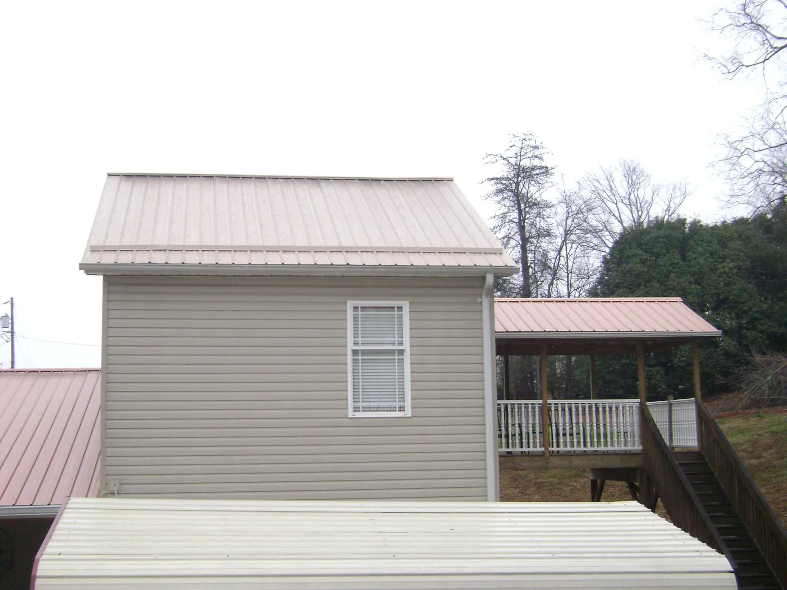 Tan metal roofs on a two story addition and attached porch, from a Roof Replacement job in Ho Ho Kus