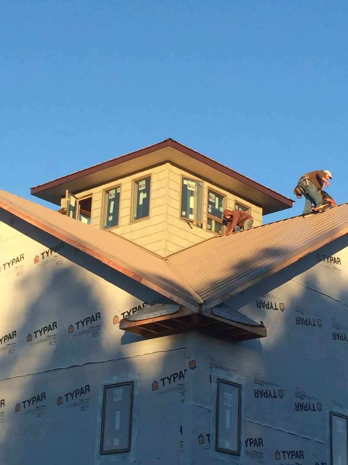 Roofers working around a rooftop cupola on a new metal roof at sunset — Roof Waterproofing in Ho Ho Kus by Roofing Brothers